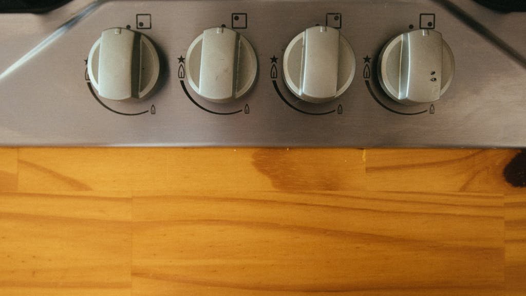 A close-up view of modern stove control knobs on a wooden countertop.